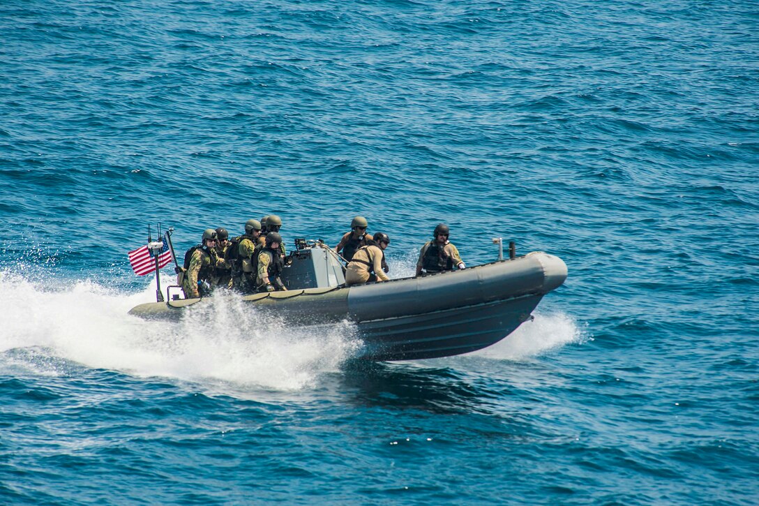 Sailors operate a small combat boat in the ocean.