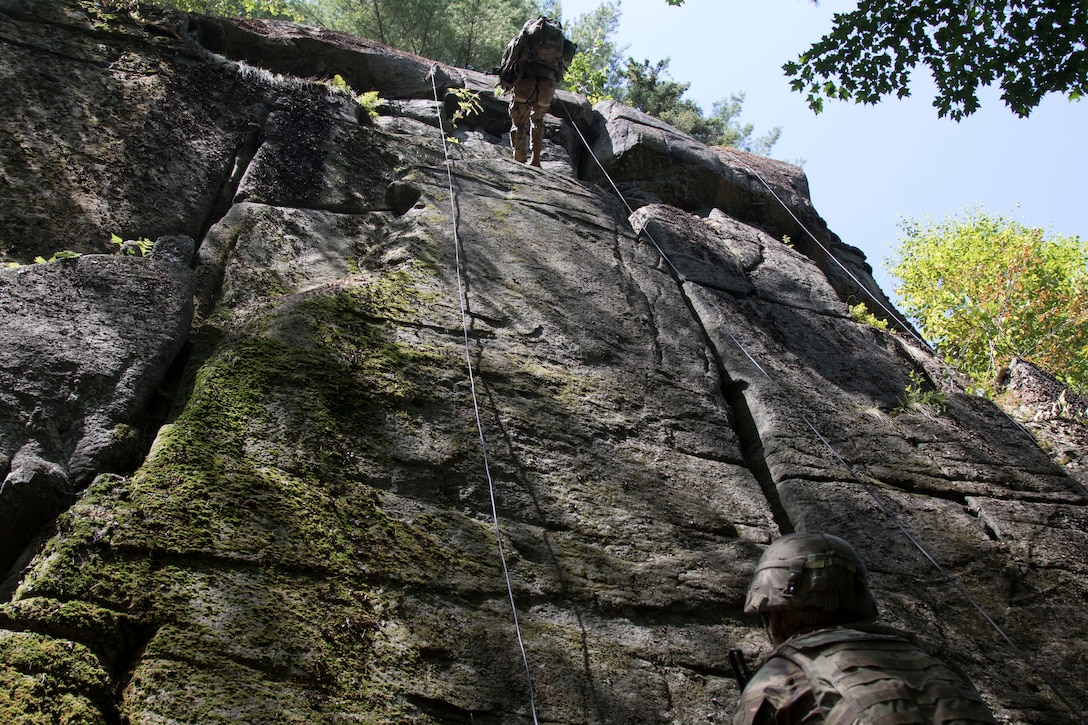 A soldier climbs a rock wall.