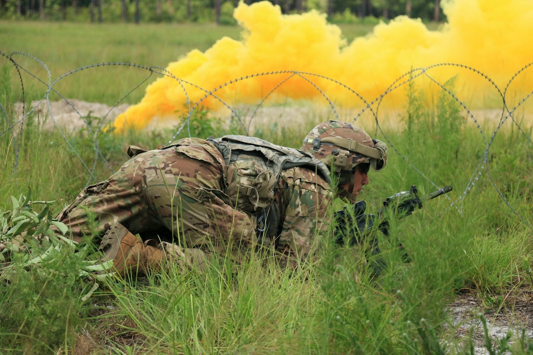 A soldier crawls in grass.