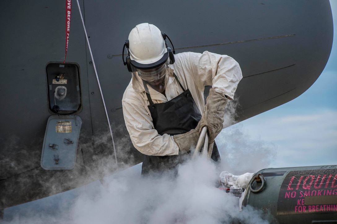 An airman pours liquid oxygen into an aircraft.