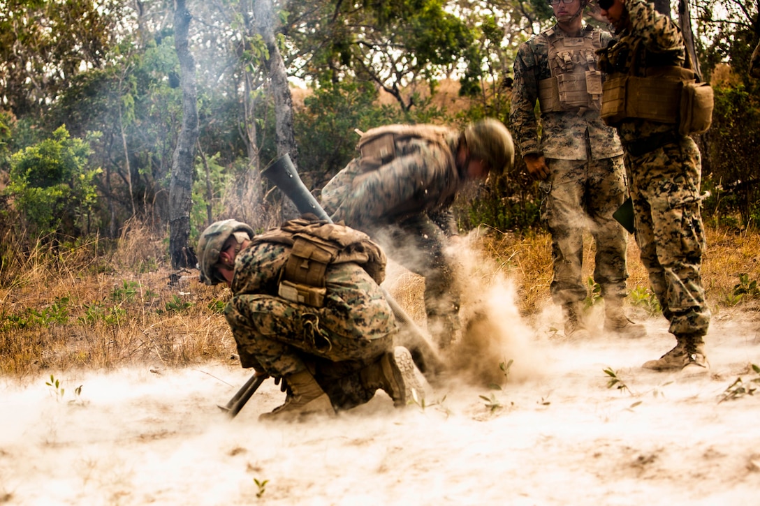 Two Marines fire a weapon while two others stand watch.