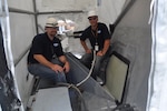 Dan Hart (left) and John Noland, engineers in the Structures and Composites Division at Naval Surface Warfare Center, Carderock Division, prepare USS Cape St. George (CG 71) for a composite patch repair in 2011. (Photo provided by Dan Hart/Released)