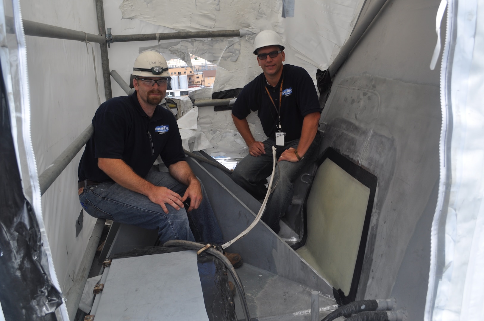 Dan Hart (left) and John Noland, engineers in the Structures and Composites Division at Naval Surface Warfare Center, Carderock Division, prepare USS Cape St. George (CG 71) for a composite patch repair in 2011. (Photo provided by Dan Hart/Released)