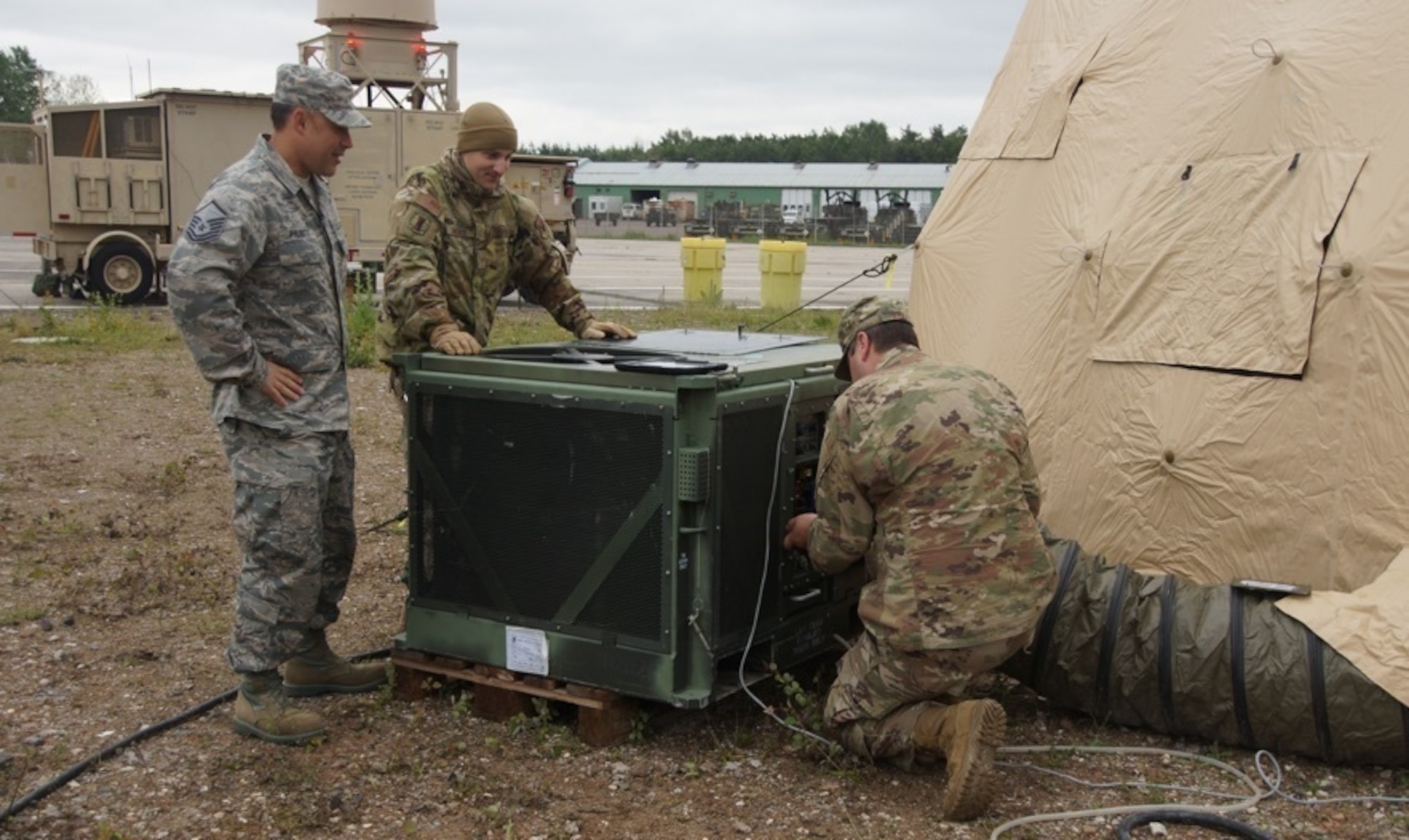 U.S. Air Force Master Sgt. Christopher Philibotte (left), Staff Sgt. James Medeiros (center) and Staff Sgt. Conner Bailey, 260th Air Traffic Controller Squadron, perform maintenance on a field deployable environmental control unit in Ramstein, Germany, June. 6th, 2019. The North Carolina Air National Guard, along with New Hampshire and Maine Air National Guard, flew to Ramstein Air Base, Germany to work with active duty 1st Combat Communications Squadron. The Air National Guard units assisted in training the active duty unit with set-up, use, and tear-down of a mobile tower and deployable tactical air navigation system. (Courtesy Photo by SrA Tsua Yang)