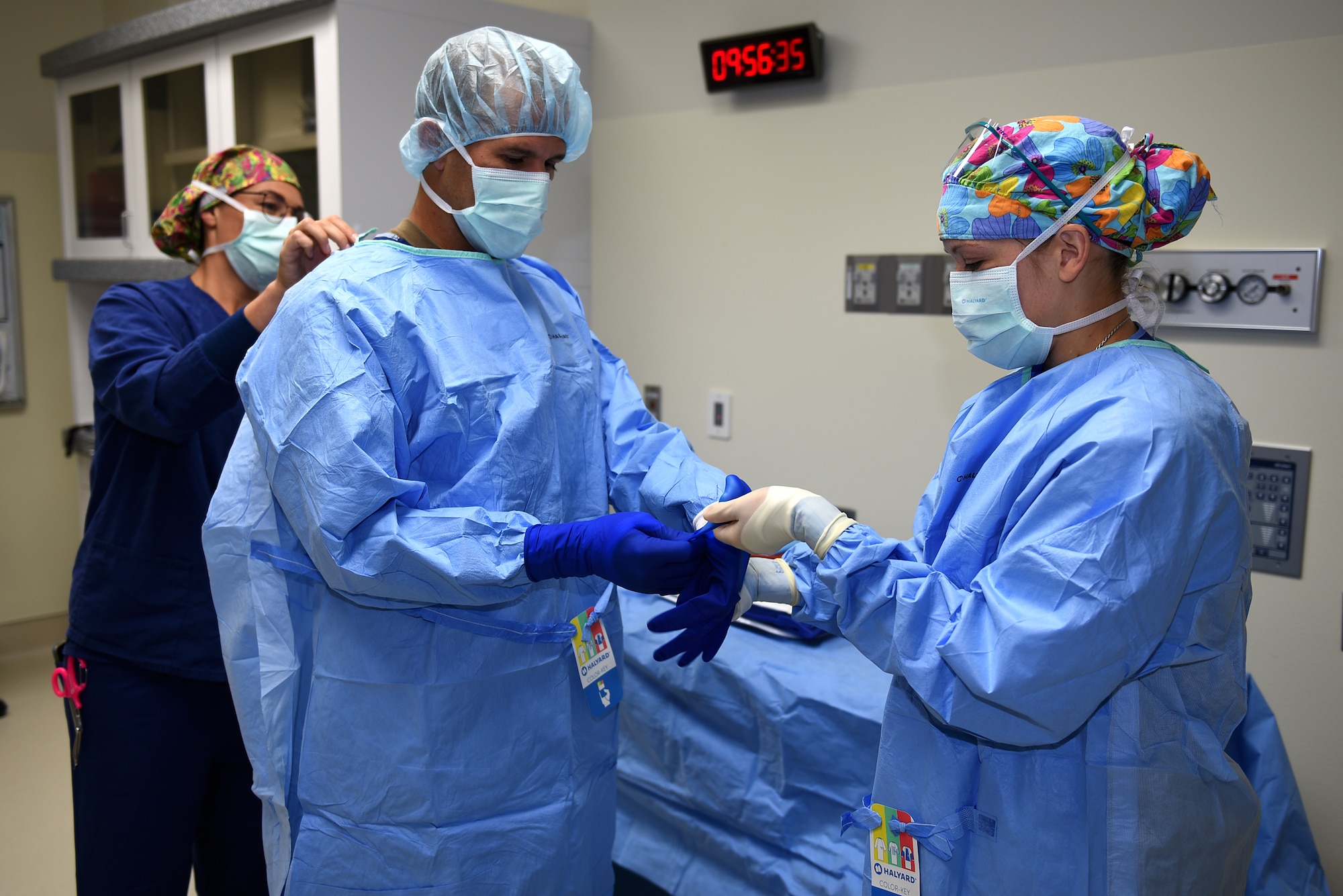 U.S. Air Force 1st Lt. Shawna Larson, left, 60th Surgical Operations Squadron operating room nurse, and Senior Airman Anjeanette Ramos, right, 60th SGCS surgical technician, help Col. Zachery Jiron, 60th Air Mobility Wing vice commander, put on a sterile gown Aug. 8, 2019, at David Grant USAF Medical Center Travis Air Force Base, California. As part of the Leadership Rounds program, Jiron participated in a simulated surgery to get a firsthand experience of all the precautions medical staff take before every surgery. (U.S. Air Force photo by Airman 1st Class Cameron Otte)