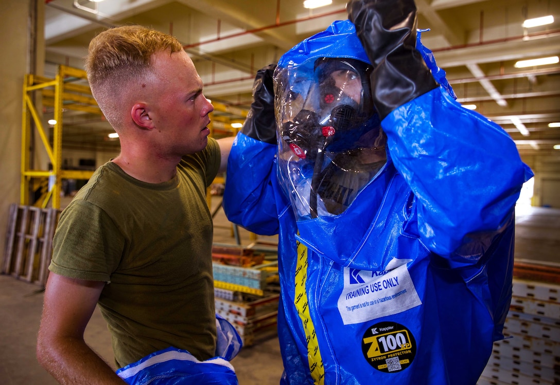U.S. Marine Corps Lance Cpl. Phoenix Drohan, left, assists Sgt. Cesar Quintero in putting on his Level-A fully encapsulated chemical protective suit at Camp Kinser, Okinawa, Japan, August 1, 2019. The suit provides the highest level of protection against unknown threats and protects wearers from substances known to damage lungs, skin and eyes. Drohan, a native of San Diego, California, and Quintero, a native of Odessa, Texas, are both CBRN defense specialists with G-3, Enhanced CBRN Section, Combat Logistics Regiment 37, 3rd Marine Logistics Group. (U.S. Marine Corps photo by Lance Cpl. Carla E. O)