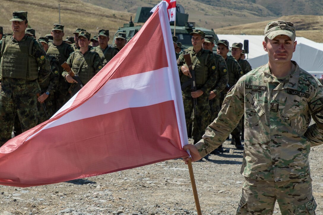 A Georgian Defense Force soldier holds the flag of Latvia