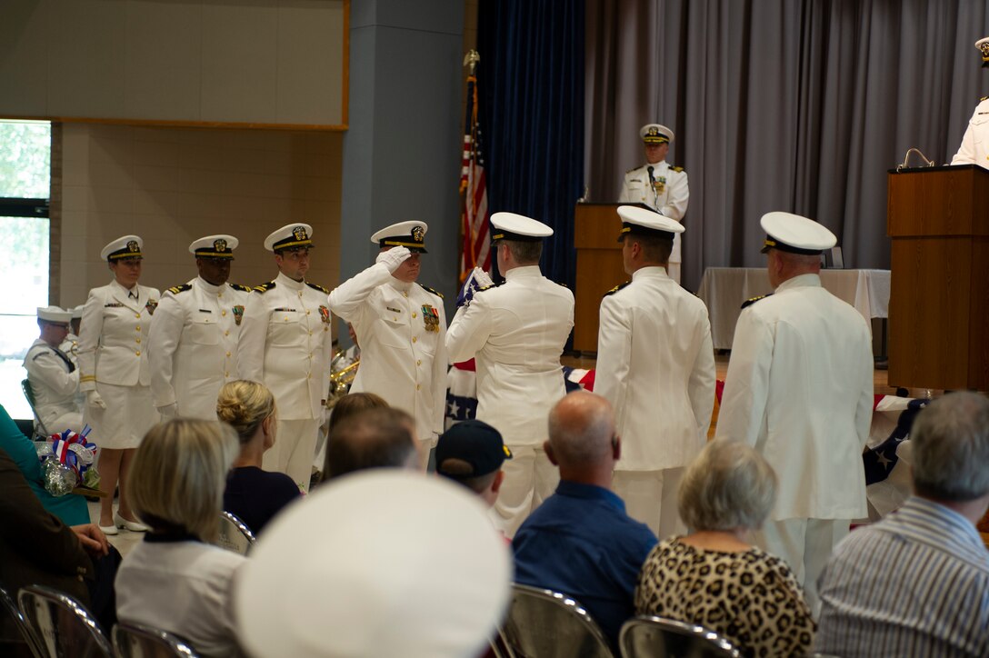 Capt. Brian D. Lawrence, right, stands ready to accept a ceremonial flag, which was flown on the future USS Tripoli (LHA 7) during building trials, at a retirement ceremony honoring his 29 years of service in the U.S. Navy Aug. 12. The retirement ceremony followed the Supervisor of Shipbuilding Gulf Coast change of command ceremony, during which Capt. Nathan A. Schneider assumed command.