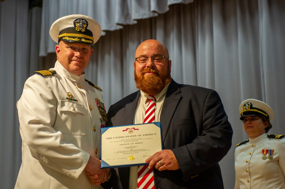 Capt. Brian D. Lawrence, left, accepts a Legion of Merit award from Mr. Mathew Sermon, Executive Director of the Amphibious, Auxiliary and Sealift Office during the Supervisor of Shipbuilding Gulf Coast change of command ceremony Aug. 12.