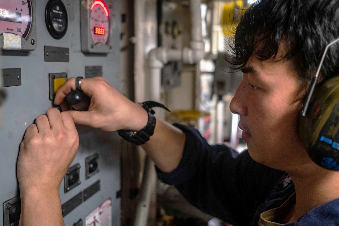 A sailor fixes a control panel.