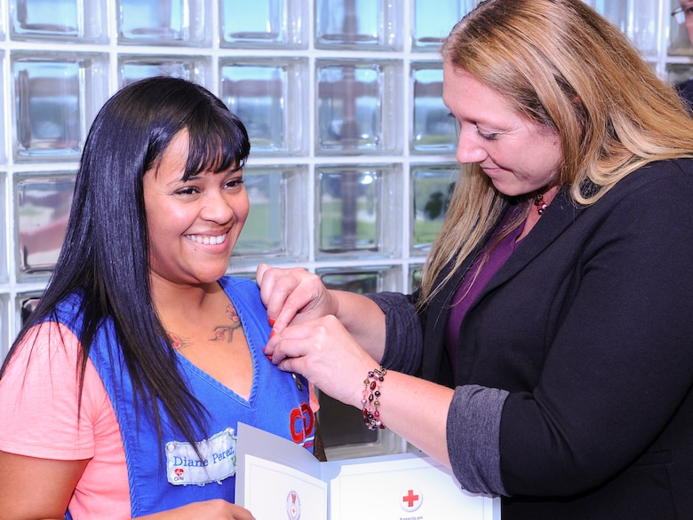 Diane Perez, left, receives the American Red Cross Certificate of Merit pin from Jessica Parks, Air Force Academy Child Development Center director, Aug. 13, 2019, at the U.S. Air Force Academy, Colo. The Certificate of Merit is the highest award given by the Red Cross to an individual who saves or sustains a life; it’s signed by the President of the United States. (U.S. Air Force photo by Tech. Sgt. Charles Rivezzo)