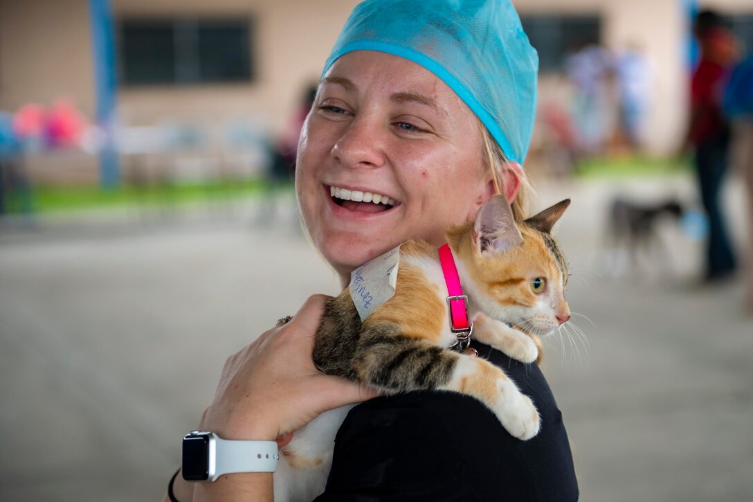 A service member holds a kitten on her shoulder.