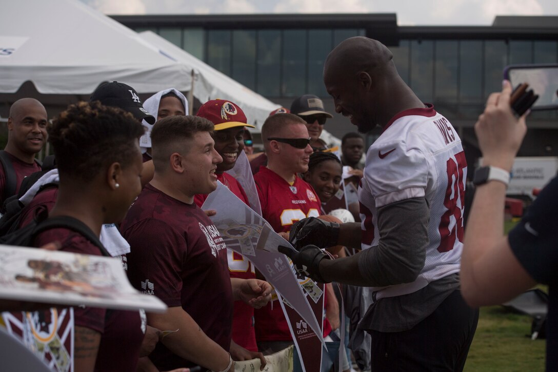 The National Football League’s Washington Redskins tight end Vernon Davis, signs memorabilia for service members during USAA’s Salute to Service NFL Boot Camp event at the Bon Secours Washington Redskins Training Center, Richmond, Virginia, Aug. 6, 2019.