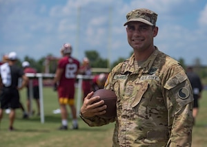 U.S. Army Chief Warrant Officer Darrell Busquets, 2nd Battalion, 224th Aviation Regiment UH-60 Black Hawk instructor pilot, holds a football during USAA’s Salute to Service NFL Boot Camp event at the Bon Secours Washington Redskins Training Center, Richmond, Virginia, Aug. 6, 2019.