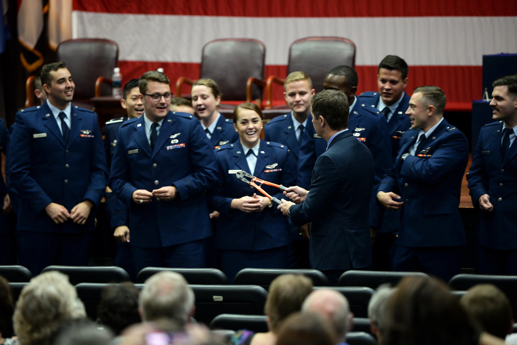 Steve Broderick, spouse of Col. Samantha Weeks, 14th Flying Training Wing commander, hands graduates a pair of bolt cutters to help break their first set of wings following Specialized Undergraduate Pilot Training Class’s 19-19/20 graduation in the Kaye Auditorium July 26, 2019, on Columbus Air Force Base, Miss. Breaking of the wings is a tradition for new pilots, as one half is kept by the pilot and the other by a loved one. The two halves are not brought together until the pilot’s death. (U.S. Air Force photo by Airman Hannah Bean)