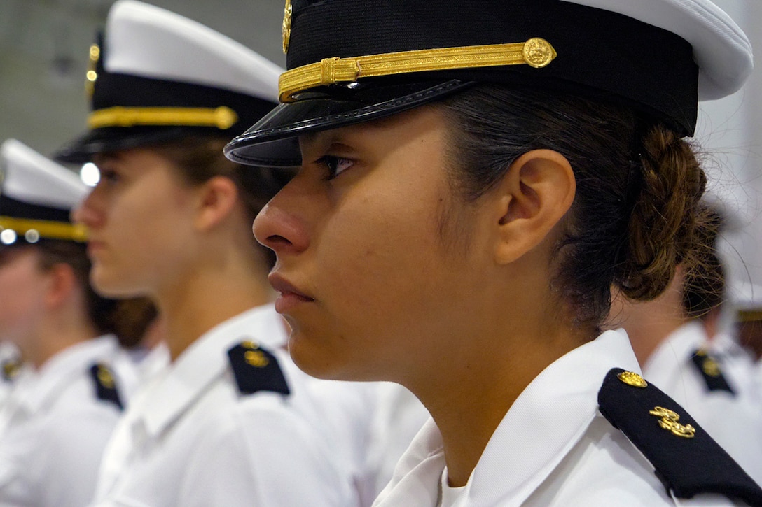 Women in military uniforms stand at attention.