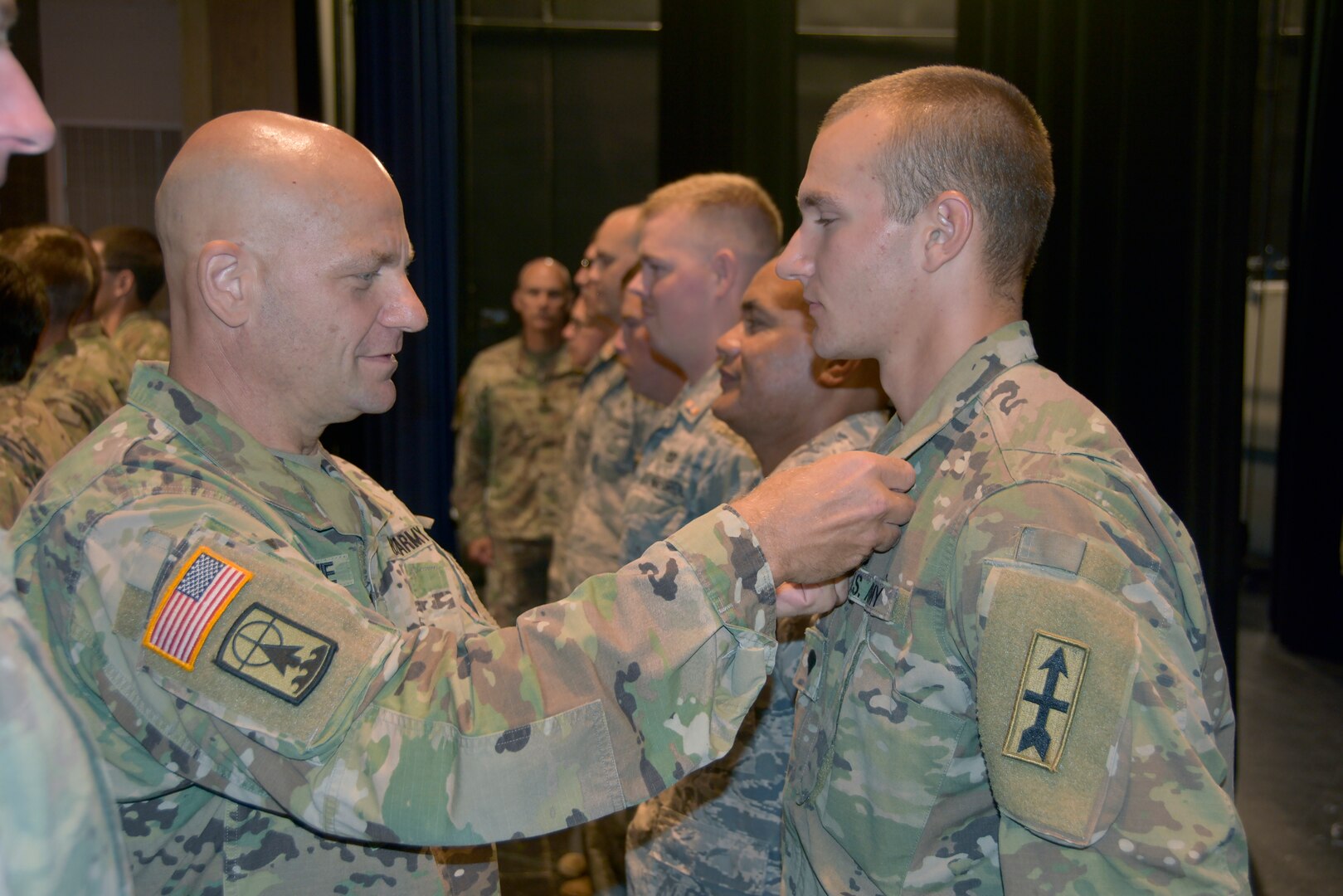 Brig. Gen. David Odonahue, Wisconsin's deputy adjutant general for civil support, pins the Wisconsin National Guard Emergency Service Ribbon on the collars of approximately 150 Wisconsin National Guard Soldiers and Airmen during an Aug. 10, 2019, ceremony at Unity High School in Balsom Lake, Wis. The Guard members helped clear storm debris from more than 50 miles of area roadways in the weeks following strong summer storms July 19.