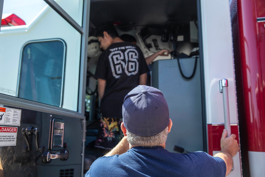 Kevin Brown, a Captain with the Miramar Fire Station, shows the youth from the Boys and Girls Club Miramar the inside of a fire truck at Marine Corps Air Station Miramar, Calif., Aug. 12. The Boys and Girls Club Miramar youths visited MCAS Miramar Station 61 to understand the importance of firefighting. (Marine Corps photo by Lance Cpl. Cheng Chang)