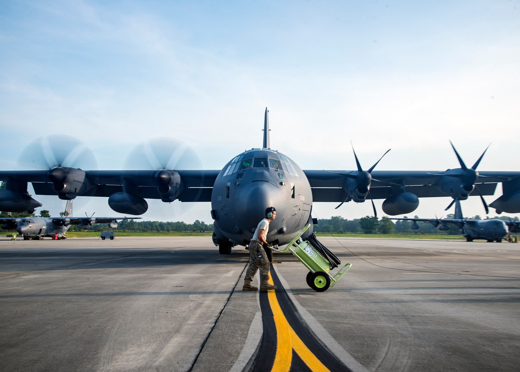 An Airman from the 71st Aircraft Maintenance Unit (AMU) pushes a fire bottle across the flight line, Aug. 13, 2019, at Moody Air Force Base, Ga. Airmen from the 71st AMU perform various tasks prior to take off to ensure the aircraft is performing optimally to complete its mission of supporting the 71st Rescue Squadron. Those tasks consist of: pre-flight inspection, removing plugs and cover, repairing any problems found during crew pre-flight checks as well as marshaling the aircraft for takeoff. (U.S. Air Force photo by Airman 1st Class Eugene Oliver)