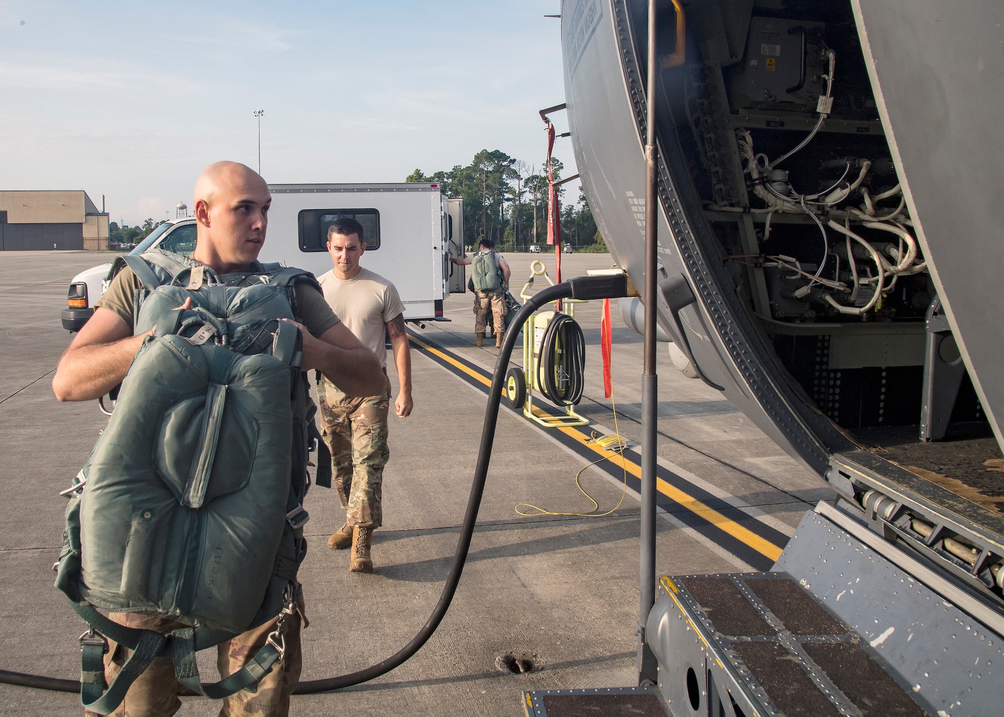 Airman 1st Class Gary Scott, left, 347 Operations Support Squadron aircrew flight equipment (AFE) apprentice, carries AFE onto an HC-130J Combat King II, Aug. 13, 2019, at Moody Air Force Base, Ga. Airmen from the 71st Aircraft Maintenance Unit and other supporting units perform various tasks prior to takeoff to ensure the aircraft is performing optimally to complete its mission of supporting the 71st Rescue Squadron. Those tasks consist of: pre-flight inspection, securing equipment, removing plugs and cover, repairing any problems found during crew pre-flight checks as well as marshaling the aircraft for takeoff. (U.S. Air Force photo by Airman 1st Class Eugene Oliver)