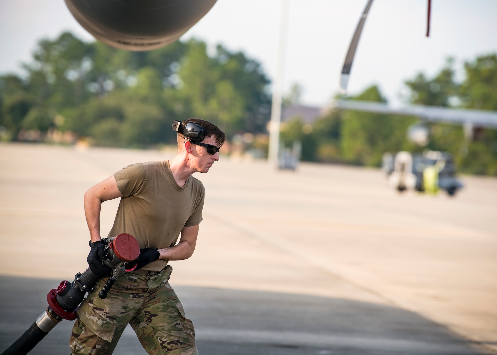 Airman 1st Class Steven Raulston, 23d Logistics Readiness Squadron fuels distribution operator, carries a fuel line hose, Aug. 13, 2019, at Moody Air Force Base, Ga.  Airmen from the 71st Aircraft Maintenance Unit and other supporting units perform various tasks prior to takeoff to ensure the aircraft is performing optimally to complete its mission of supporting the 71st Rescue Squadron. Those tasks consist of: pre-flight inspection, removing plugs and cover, fueling the aircraft, repairing any problems found during crew pre-flight checks as well as marshaling the aircraft for takeoff. (U.S. Air Force photo by Airman 1st Class Eugene Oliver)
