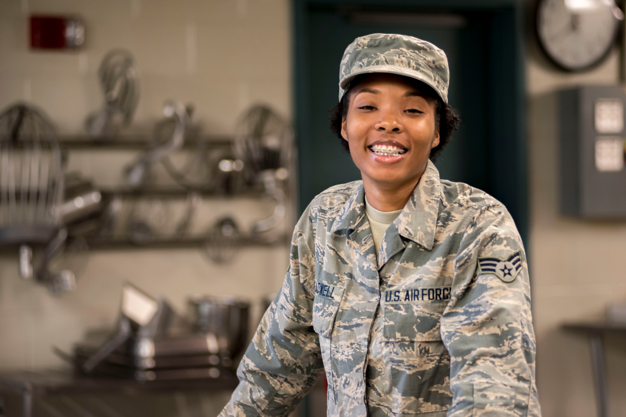 Airman posing for a photo in with kitchen equipment in the background