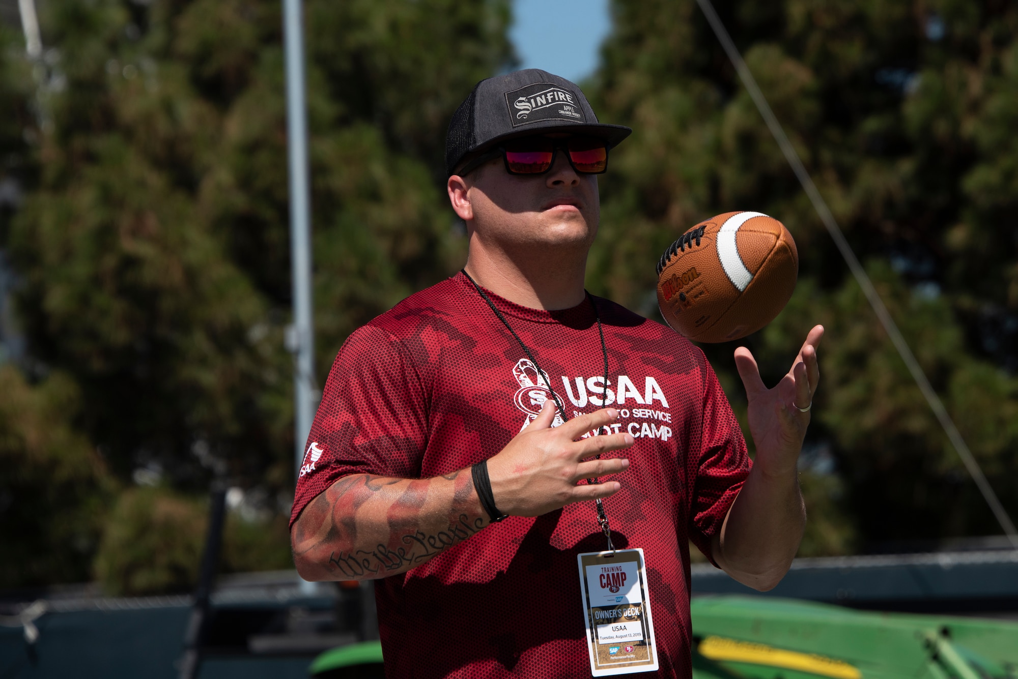 U.S. Air Force Tech. Sgt. Timothy Brown, 860th Aircraft Maintenance Squadron debrief noncommissioned officer in charge, watches a San Francisco 49ers practice Aug. 13, 2019, while tossing a football up and down during the Salute to Service Boot Camp in Santa Clara, California. Fifty Airmen attended the event from numerous units. The event provided Airmen with an opportunity to interact with NFL players and compete against one another in a variety of athletic drills. (U.S. Air Force photo by Tech. Sgt. James Hodgman)