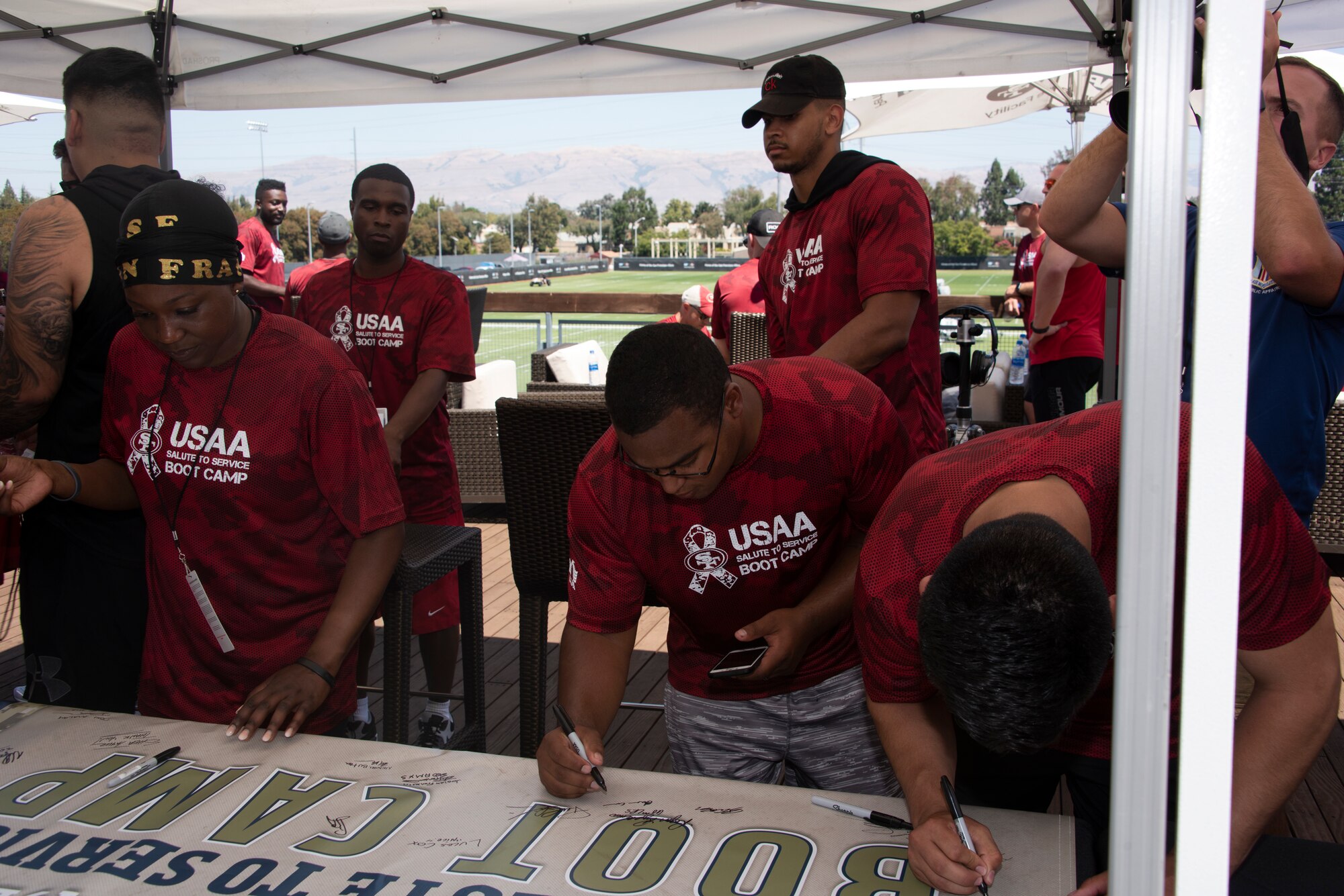 U.S. Air Force Airmen from Travis Air Force Base, California, sign a ‘Salute to Service’ banner Aug. 13, 2019, during the Salute to Service Boot Camp in Santa Clara, California. The event provided Airmen with an opportunity to interact with NFL players and compete against one another in a variety of athletic drills. (U.S. Air Force photo by Tech. Sgt. James Hodgman)