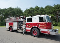U.S. Air Force Airman 1st Class Adam Cardona, a 35th Civil Engineer Squadron fire protection journeyman, poses for a photo on a fire truck at Misawa Air Base, Japan, Aug. 7, 2019. Cardona has been stationed at Misawa AB for a year and a half and enjoys readiness training exercises with his shop because it enhances his work skillset, knowledge and understanding. (U.S. Air Force photo by Senior Airman Collette Brooks)