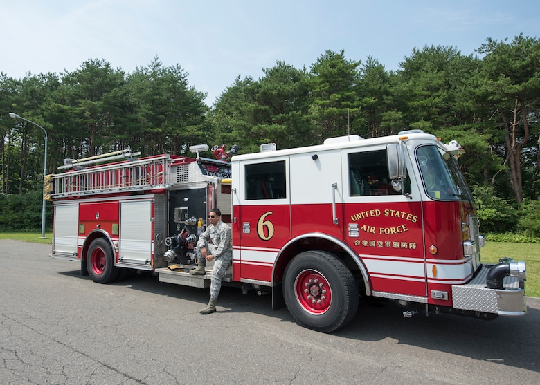 U.S. Air Force Airman 1st Class Adam Cardona, a 35th Civil Engineer Squadron fire protection journeyman, poses for a photo on a fire truck at Misawa Air Base, Japan, Aug. 7, 2019. Cardona has been stationed at Misawa AB for a year and a half and enjoys readiness training exercises with his shop because it enhances his work skillset, knowledge and understanding. (U.S. Air Force photo by Senior Airman Collette Brooks)