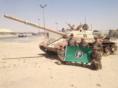 Members of the 122D Public Affairs Operations Center pose in front of a disabled  tank at Camp Arifjan, Kuwait. Arifjan is known as "The Gateway" because Soldiers heading into theater must first check in through Kuwait. From left to right: Master Sgt. Neal Mitchell, Capt. James Deakins, Col. Stanley Seo, Capt. Benjamin Burbank and Maj. Eric Trovillo.