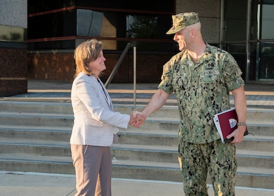 Navy Admiral greets Defense Logistics Agency Chief of Staff  in front of Land and Maritime Headquarters building.