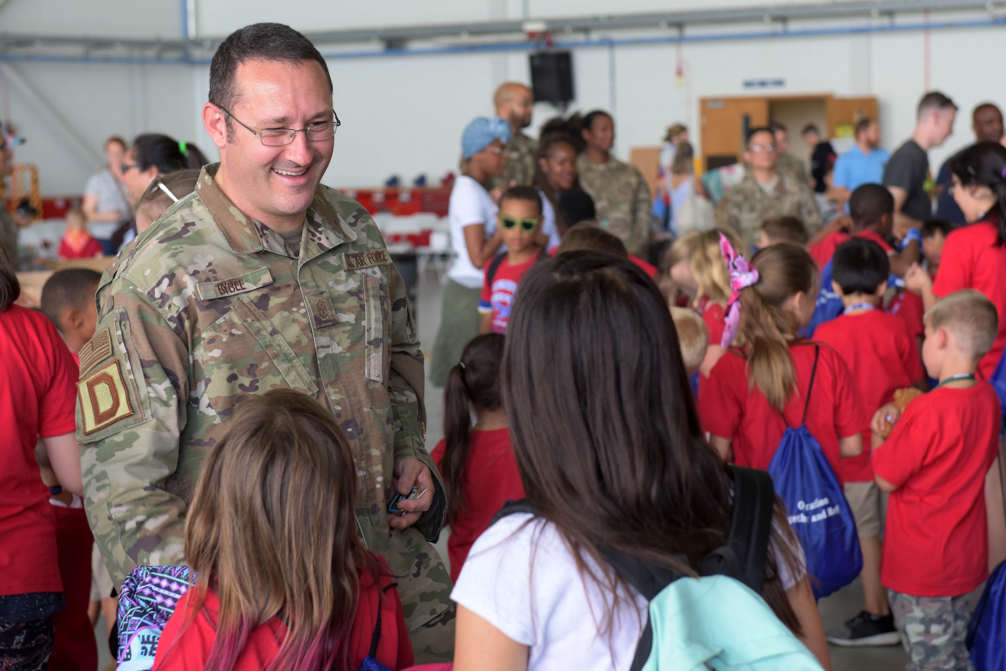 Master Sgt. Jeremiah Bybee, 100th Comptroller Squadron first sergeant, presents a coin to a child during the ‘kids deployment line’ at RAF Mildenhall, England, Aug. 9, 2019. All of the children present received a coin from one of the wing’s first sergeants. (U.S. Air Force photo by Senior Airman Benjamin Cooper)