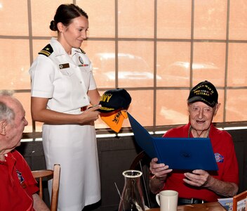 Navy Lt. j.g. Kathleen Spyrnal, an officer programs operations officer assigned to Navy Recruiting District San Antonio, presented a certificate of appreciation to World War II Merchant Marine Ray Denison during an Alamo Honor Flight Breakfast Aug. 14. Attended by other WWII veterans, the breakfast also served as a venue to celebrate Denison’s 100th birthday.