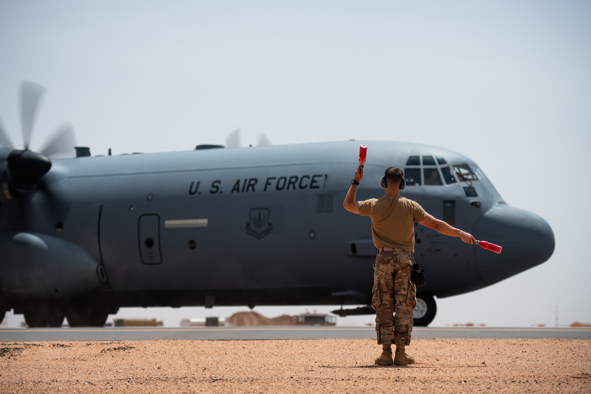 U.S. Air Force Tech. Sgt. Daniel Peterson, 724th Expeditionary Air Base Squadron air terminal operations center non-commissioned officer in charge, marshals a C-130J Super Hercules at Nigerien Air Base 201, Agadez, Niger, Aug. 3, 2019. This was the first C-130 to take-off at Air Base 201, marking the beginning of limited Visual Flight Rules operations at the base. (U.S. Air Force photo by Staff Sgt. Devin Boyer)
