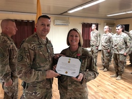 Col. Justin Osberg, commander of 108th Sustainment Brigade, congratulates Chief Warrant Officer 3 Nicole Matteson after presenting her the Military Outstanding Volunteer Service Medal at Camp Taji, Iraq, Aug. 10, 2019. Matteson volunteered over a four year period as a Den Leader with the Boy Scouts of America, Cub Scout Pack 38.