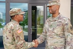 A staff sergeant greets a specialist. The Army is now requiring that Soldiers be assigned a sponsor before any move.