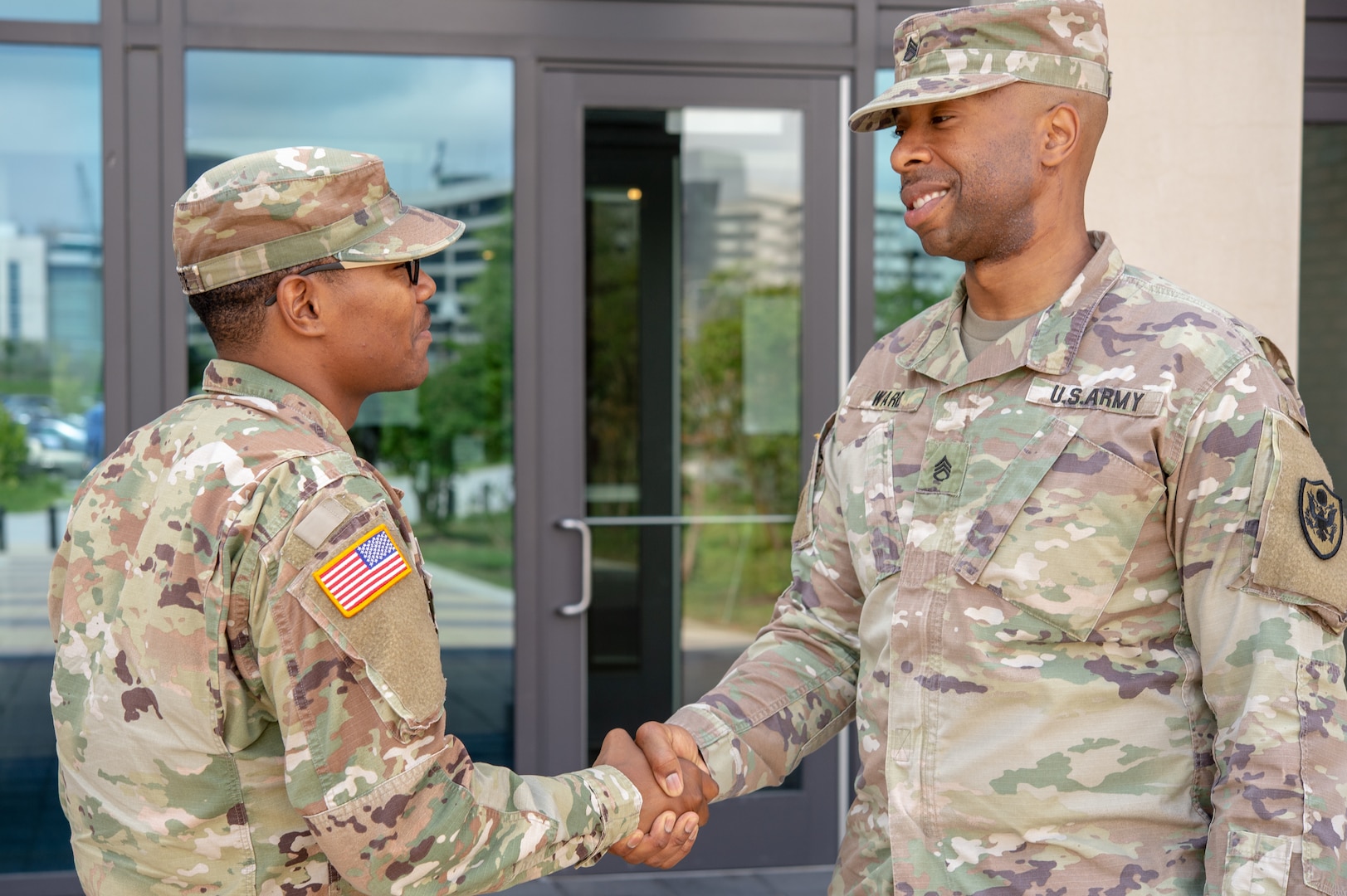 A staff sergeant greets a specialist. The Army is now requiring that Soldiers be assigned a sponsor before any move.
