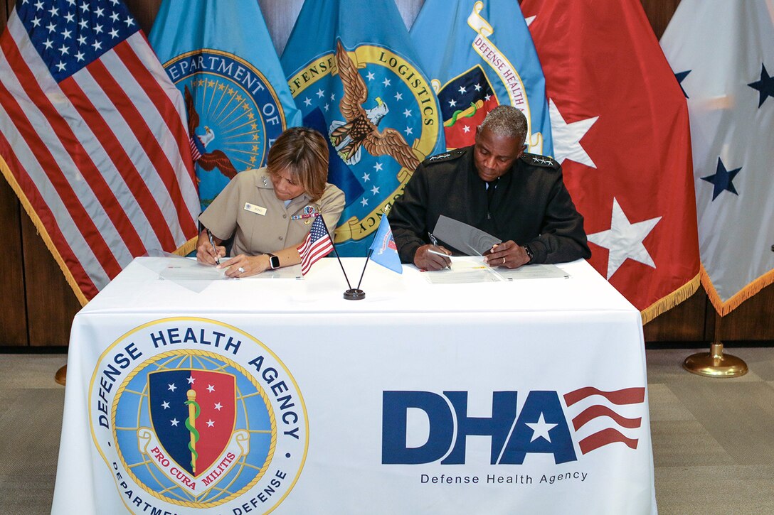Navy Vice Adm. Raquel Bono, DHA Director, left, and Army Lt. Gen. Darrell K. Williams, DLA Director, right, sign a memorandum of agreement Aug. 15, 2019 at the DHA headquarters in Falls Church, Virginia.