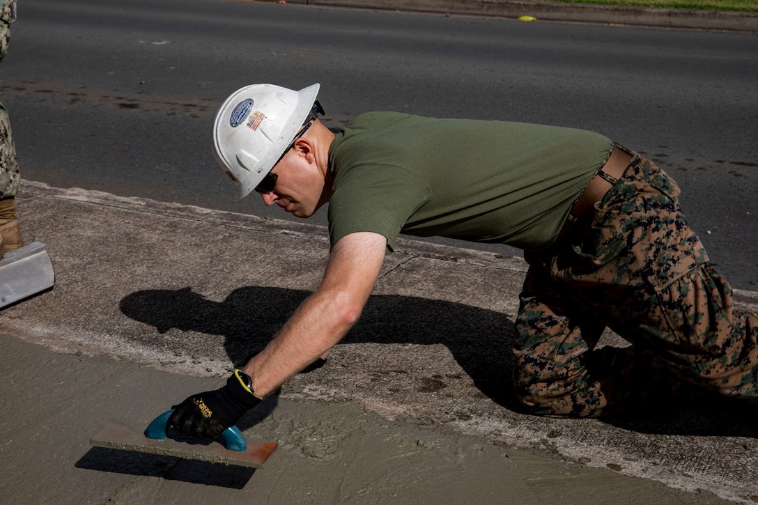 U.S. Marine Corps Capt. Mark Dougherty, the executive officer of Charlie Company, 3rd Battalion, 3d Marine Regiment, scrapes concrete, Marine Corps Base Hawaii (MCBH), Aug. 2, 2019. U. S. Navy and Marine Corps personnel worked together to widen a sidewalk on Lawrence Rd. in order to increase safety within the MCBH community (U.S. Marine Corps photo by Pfc. Samantha Sanchez)