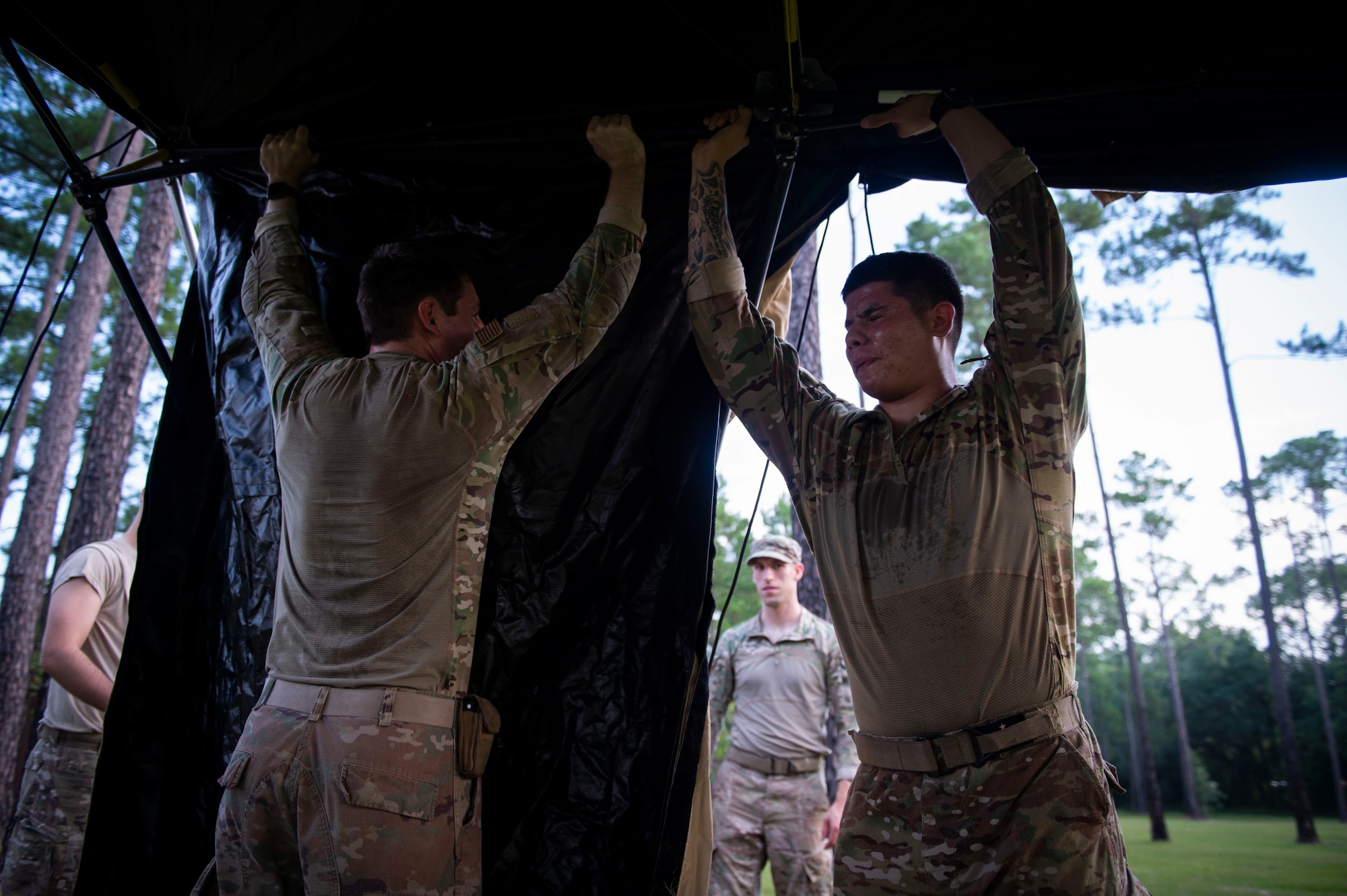 Senior Airman Tristan Wiese, left, 824th Base Defense Squadron (BDS) fire team member, and Senior Airman Fernie Salazar, 824th BDS fire team leader set up a tent during a tactical leaders course, Aug. 10, 2019, at Moody Air Force Base, Ga. The 7-day course revolved around squad leaders developing their skills to effectively communicate, team build and mission plan. These skills were assessed during a 36-hour simulated operation where squad leaders lead Airmen through tactical situations.  (U.S. Air Force photo by Airman Azaria E. Foster)