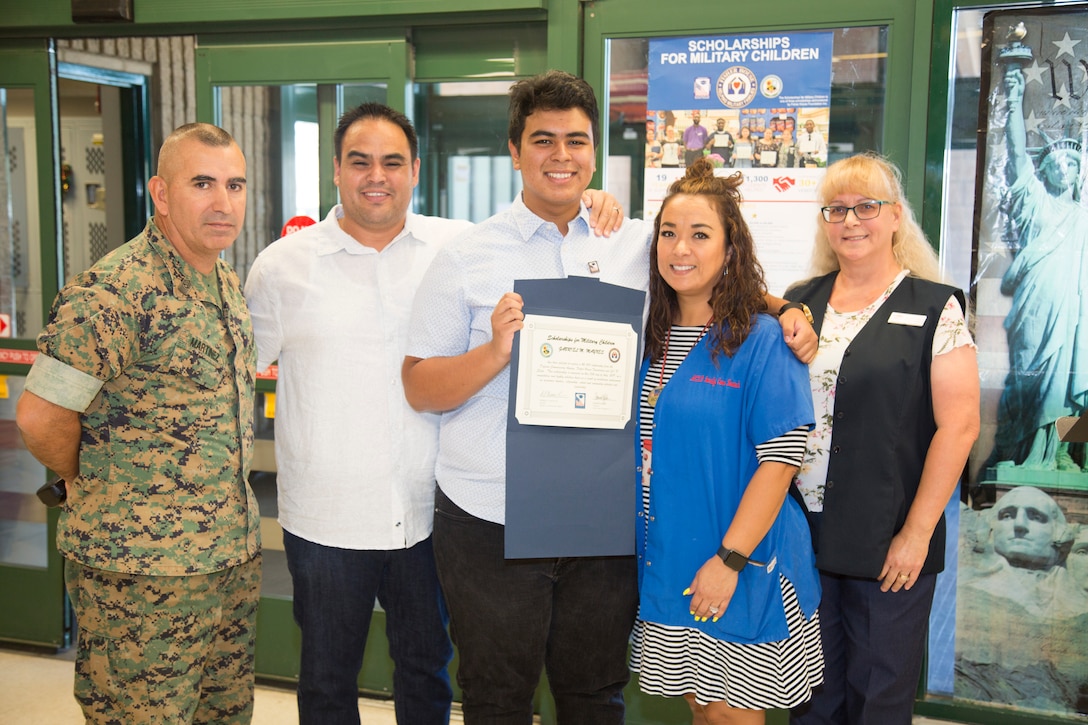 Gabriel Maynes, 17, displays the $2,000 scholarship he was awarded from the Scholarships for Military Children program administered by the Defense Commissary Agency. The ceremony was held August 13 at the MCLB Barstow,  Commissary, hosted by Jodi Dawn Ballestracci, Commissary manager, and Sgt. Maj. Sergio MartinezRuiz, base sergeant major, MCLBB. CWO3 Jose Maynes, USMC retired, and his wife Rozalyn, child care specialist, Child Development Center, MCLBB, proudly stand with their son.