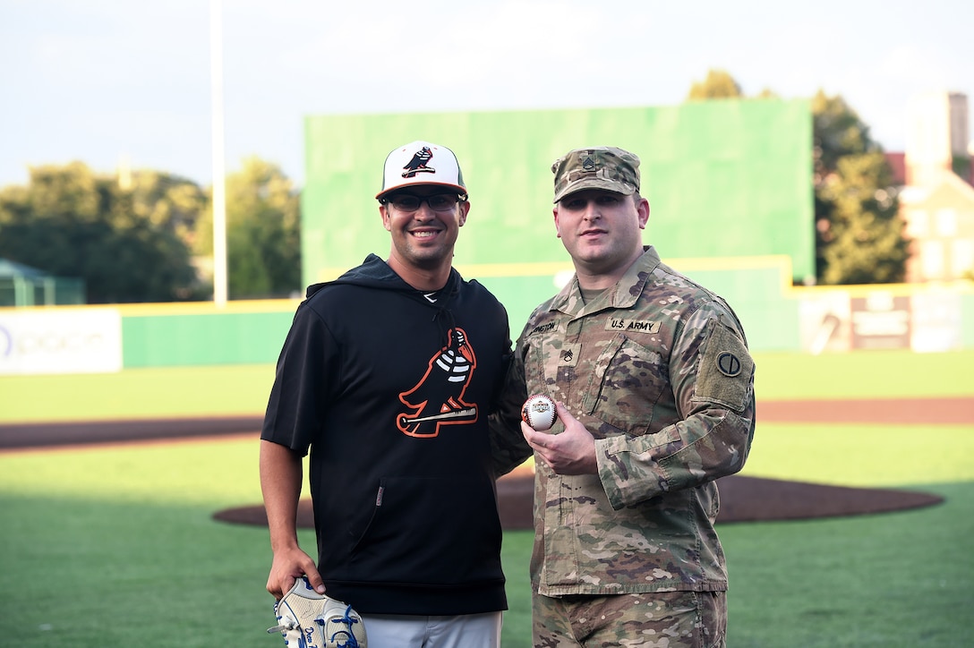 Army Reserve Staff Sgt. Clifford Arrington, Information Systems noncommissioned officer assigned to the 85th U.S. Army Reserve Support Command, pauses for a photo with Drew Peden, Pitcher for Joliet Slammers, before a Joliet Slammers home game, August 13, 2019 in Joliet, Illinois.