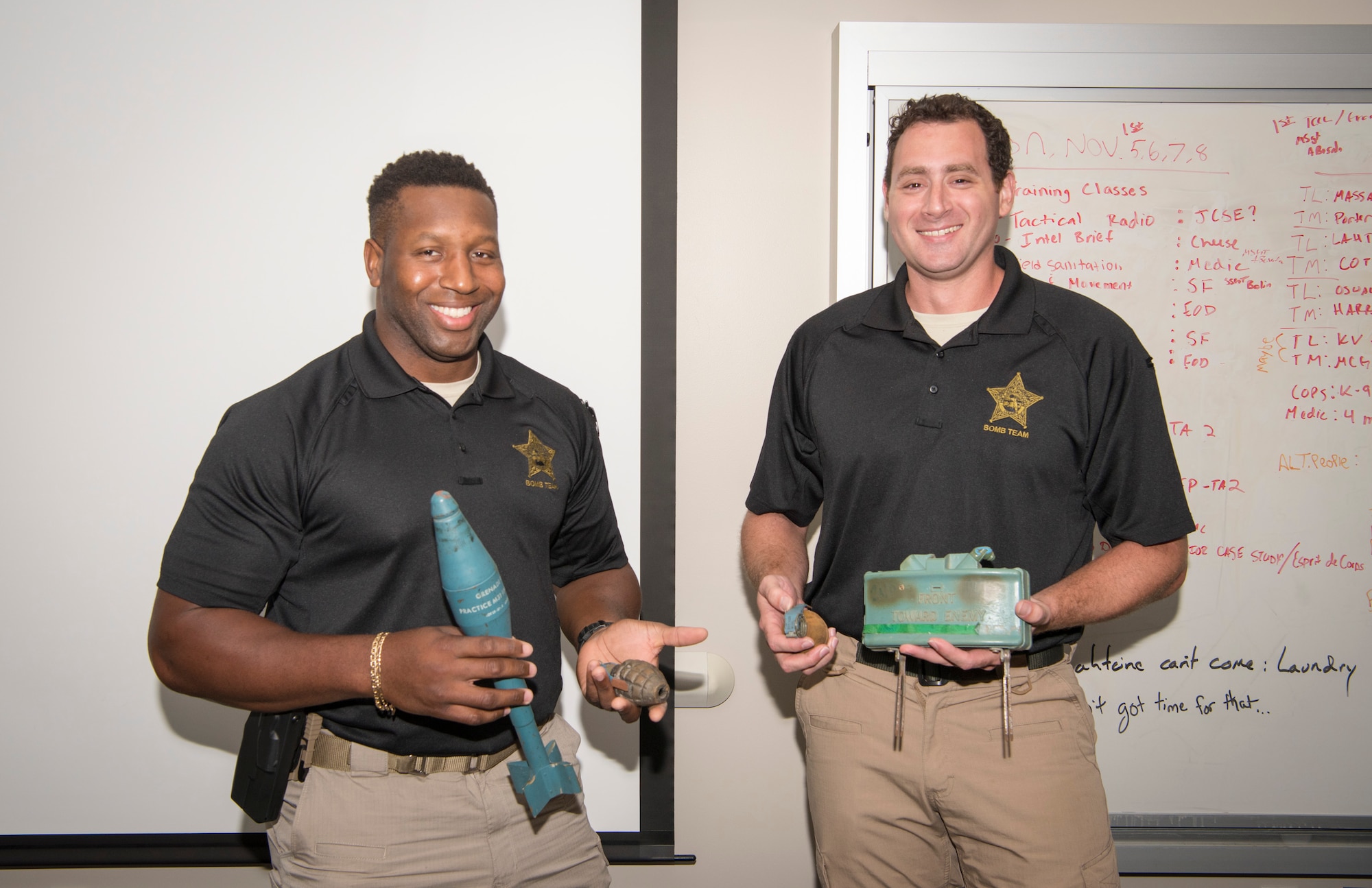 Deputy Bjar Atkins, left, and Deputy Joseph Saponara, right, both Hillsborough County Sheriff’s Office bomb technicians, hold up various types of inert military ordnance at MacDill Air Force Base, Fla., Aug. 14, 2019.