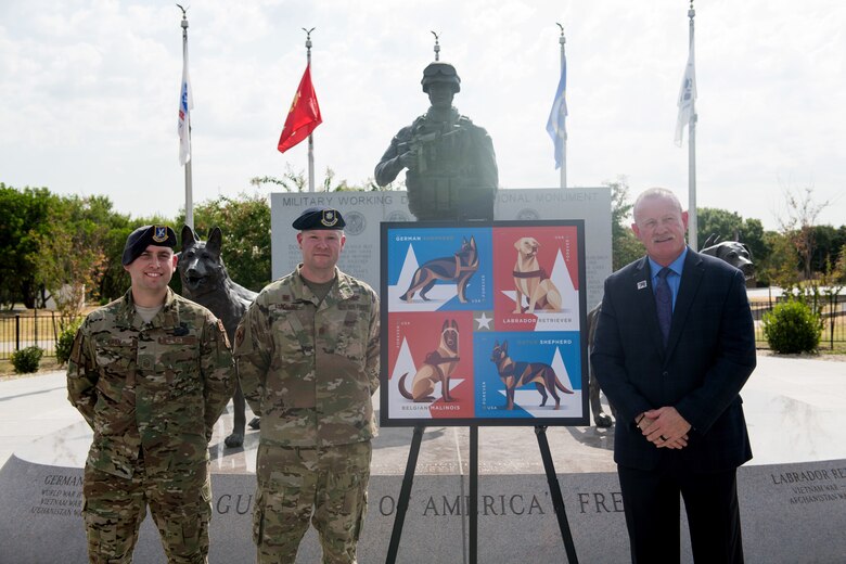 U.S. Air Force Master Sgt. Steven Kaun (left), USAF Military Working Dog program manager, Maj. Matthew Kowalski, 341st Training Squadron commander, and Robert Carr, Post Master of San Antonio, pose for a photo during the Military Working Dog Stamp ceremony Aug. 15, 2019, at Joint Base San Antonio-Medina Annex, Texas.