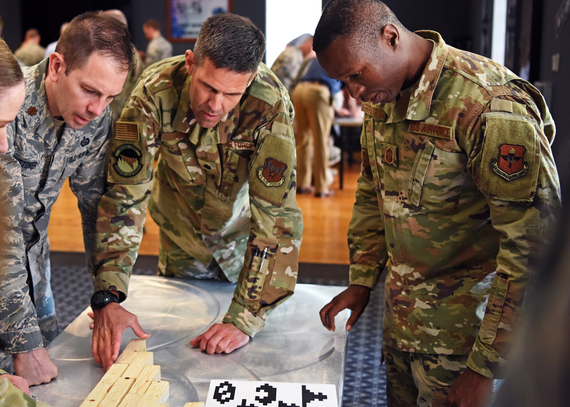 U.S. Air Force Maj. Brandon Stoker and Lt. Col. Tyler Harris from The National Air and Space Intelligence Center, work with Chief Master Sgt. Lavor Kirkpatrick, 17th Training Wing Command Chief, and 17th TRW students to solve puzzles during the mental health fitness challenge at Goodfellow Air Force Base, Texas, August 13, 2019. The challenge included physical and mental exercises to keep individuals both sharp and strong. (U.S. Air Force photo by Airman 1st Class Ethan Sherwood/Released)