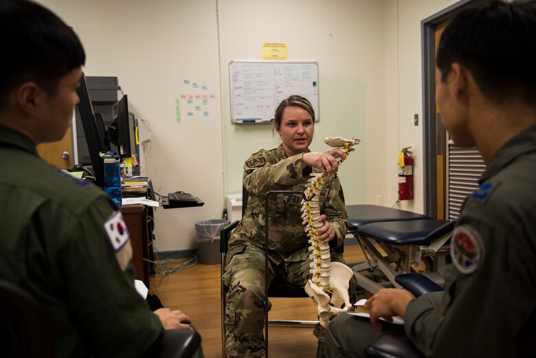 U.S. Air Force Capt. Bridgette Griffiths, 8th Medical Operations Squadron physical therapy flight commander, shows pilots from Republic of Korea Air Force’s 111th Fighter Squadron how sitting with poor posture can affect their spine during a training session at Kunsan Air Base, Republic of Korea, Aug. 9, 2019. Pilots sitting in the cockpit of fighter jets can develop back pain from staying in the position for extended periods of time. (U.S. Air Force photo by Senior Airman Stefan Alvarez)