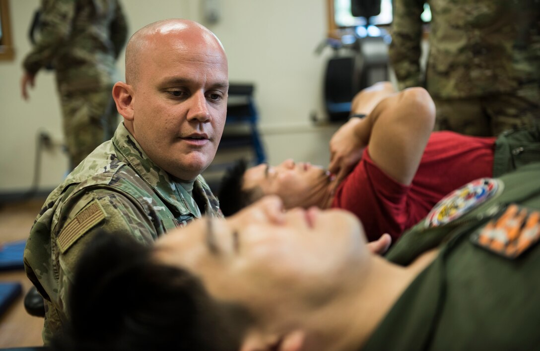 U.S. Air Force Tech. Sgt. Nicholas Ramirez, 8th Medical Operations Squadron physical therapy flight chief, teaches pilots from Republic of Korea Air Force’s 111th Fighter Squadron a way to exercise their necks during a training session at Kunsan Air Base, Republic of Korea, Aug. 9, 2019. Pilots often find themselves developing pain in different areas from regularly putting their bodies under high amounts of gravitational forces. (U.S. Air Force photo by Senior Airman Stefan Alvarez)