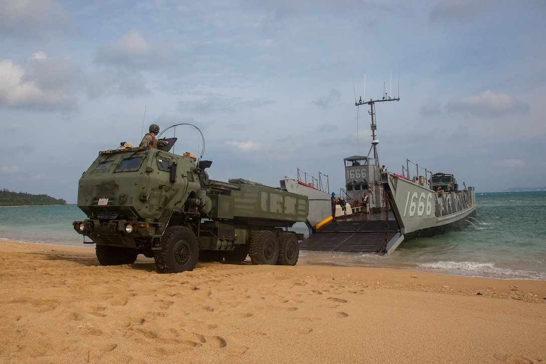 A landing craft, utility assigned to the amphibious transport dock ship USS Green Bay (LPD 20), lowers its ramp to unload a High Mobility Artillery Rocket System from 3rd Battalion, 12th Marine Regiment, 3rd Marine Division, as part of a simulated amphibious raid, at Kin Blue, Okinawa, Japan, Aug. 14, 2019. This simulated amphibious raid marks the first time that HIMARS have been inserted by landing craft, utility, demonstrating the Marine Air-Ground Task Force’s ability to conduct combined-arms maneuver from amphibious shipping.  (U.S. Marine Corps photo by Lance Cpl. Joshua Sechser)