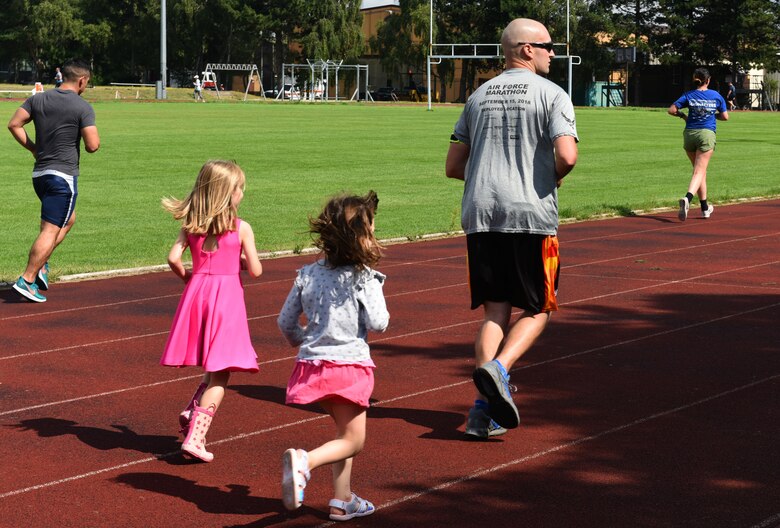 Children follow the lead of Airmen running in the Operation Warm Heart run-a-thon at Royal Air Force Lakenheath, England, Aug. 2, 2019. For each lap completed during the event, the runner's sponsors donated money, which provides emergency funds for Airmen in difficult situations. (Courtesy photo by Carissa Chae)